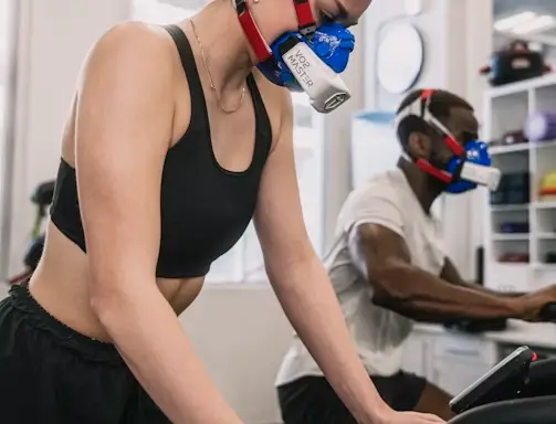 A woman wearing a mask while riding an exercise bike.