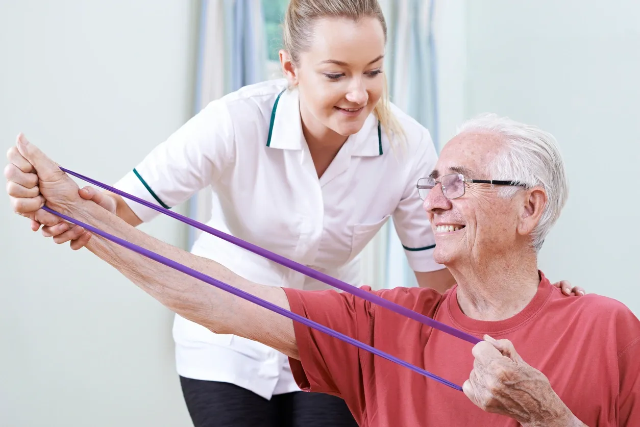 A woman helping an older man with some resistance bands