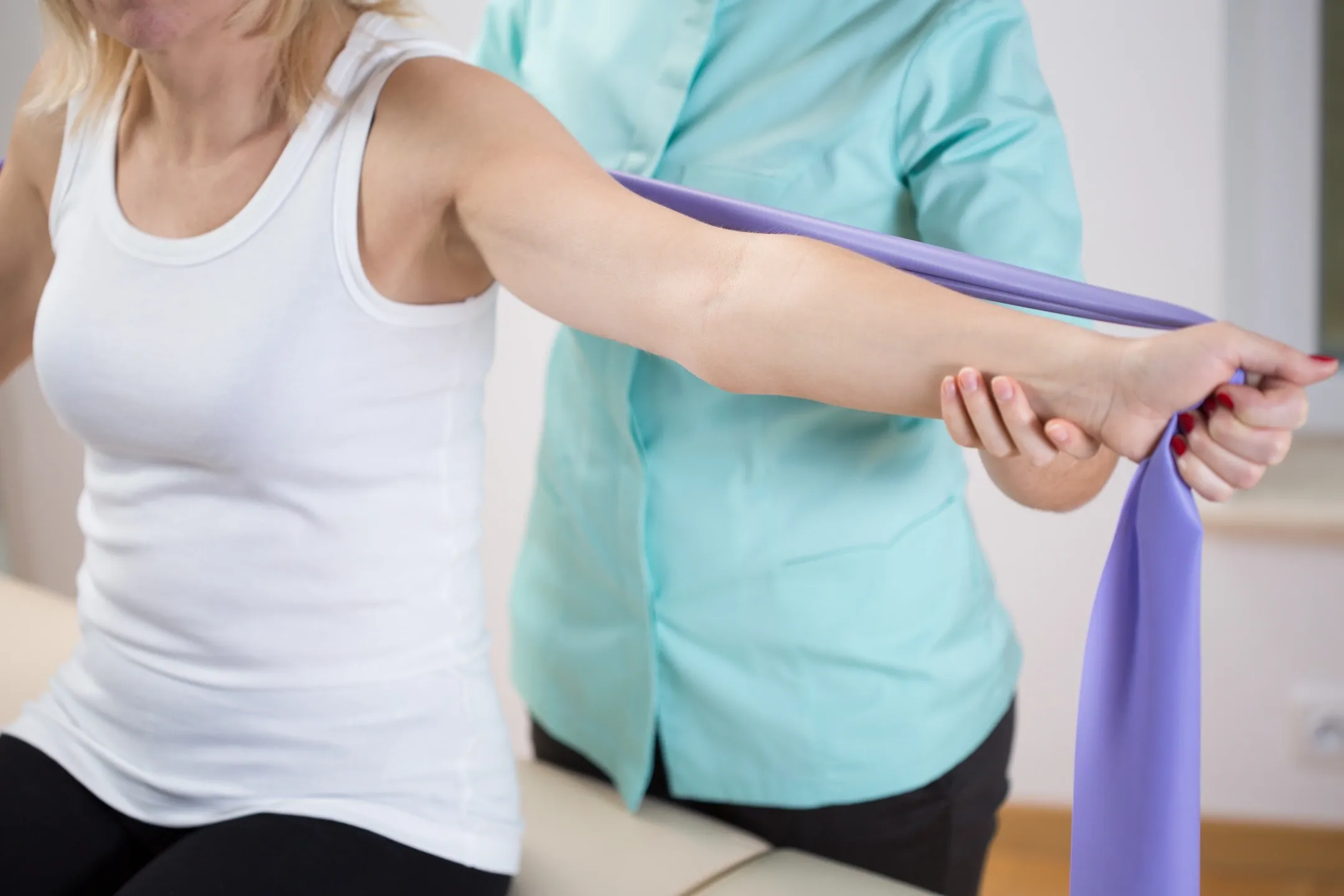 A woman is stretching her arm with a blue band.