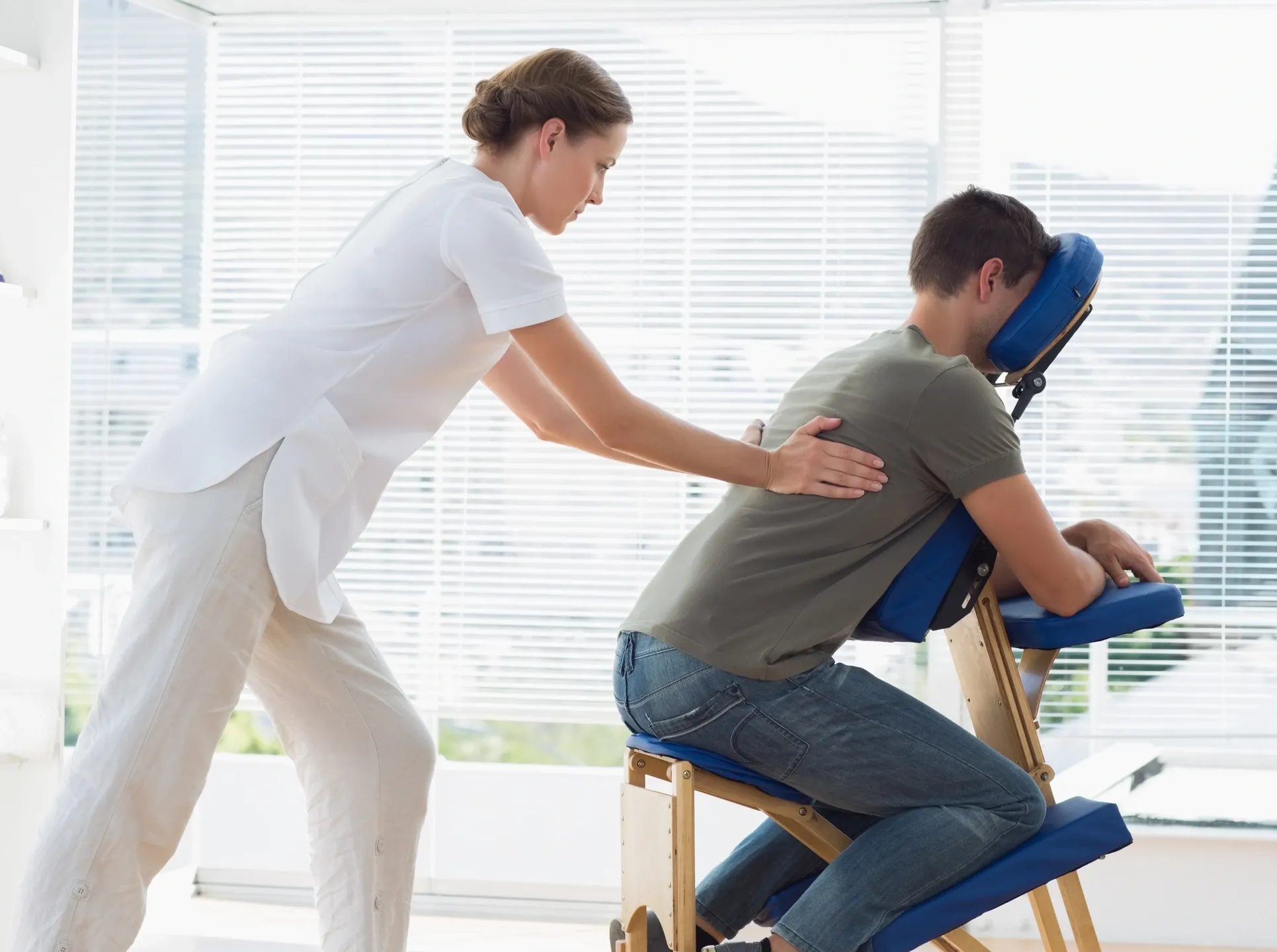 A woman is helping a man in an office chair.