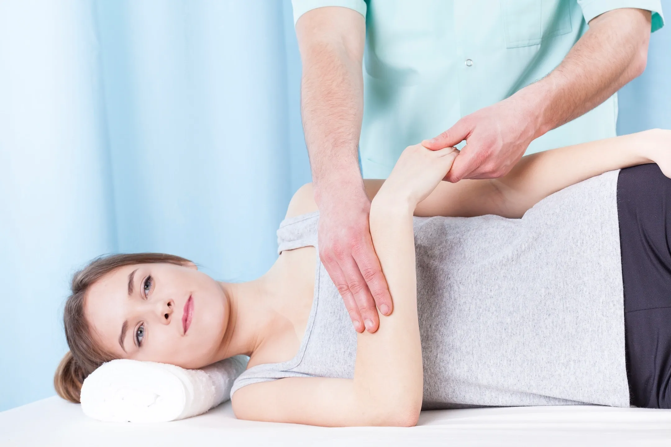 A woman getting her arm worked on by a person.