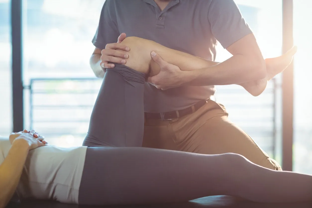 A man is holding his knee while another person sits on the ground.