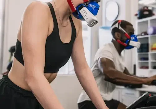 A woman wearing a mask while riding an exercise bike.