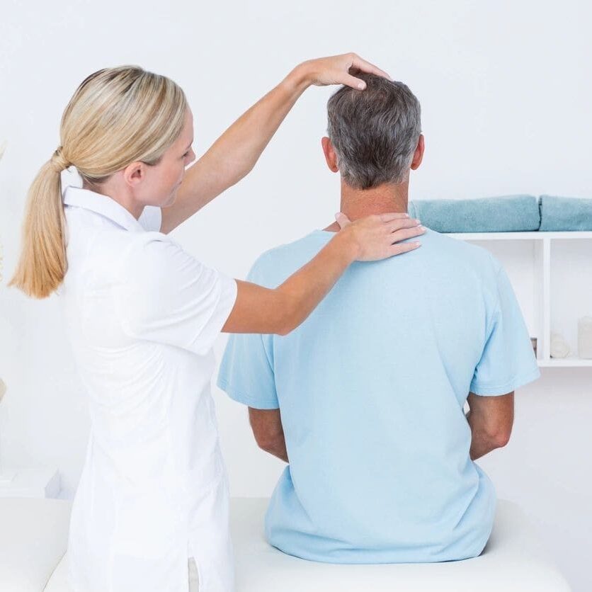 A woman is standing behind a man in the hospital.