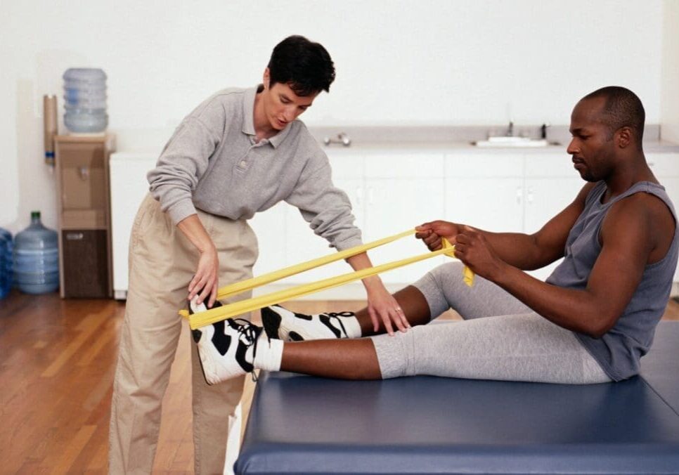 A man helping another person stretch his leg.