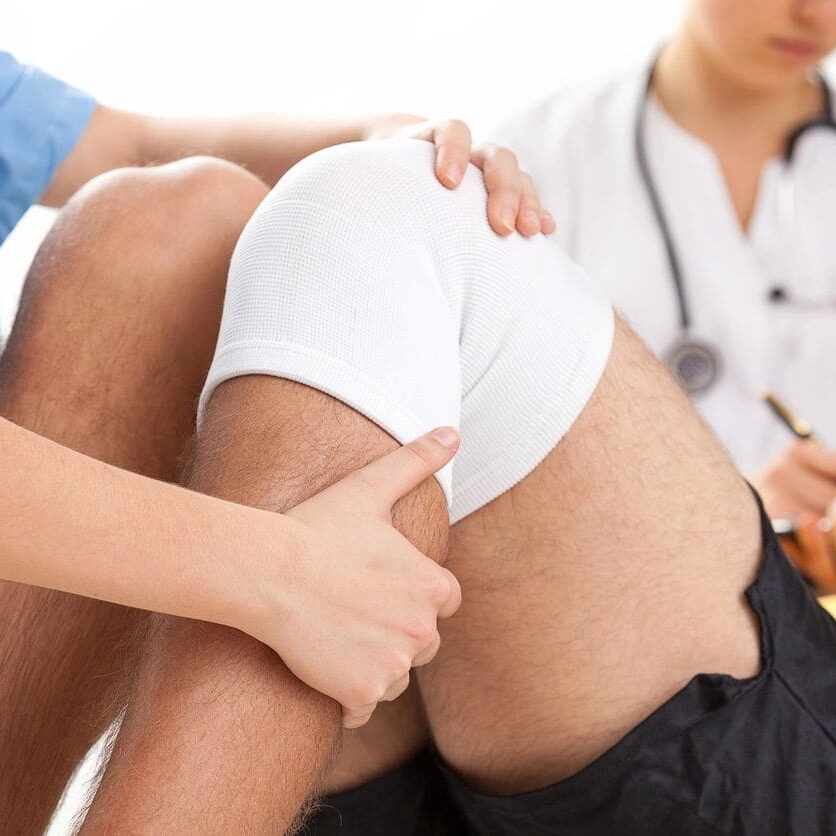A person is holding another persons leg while they are sitting down.