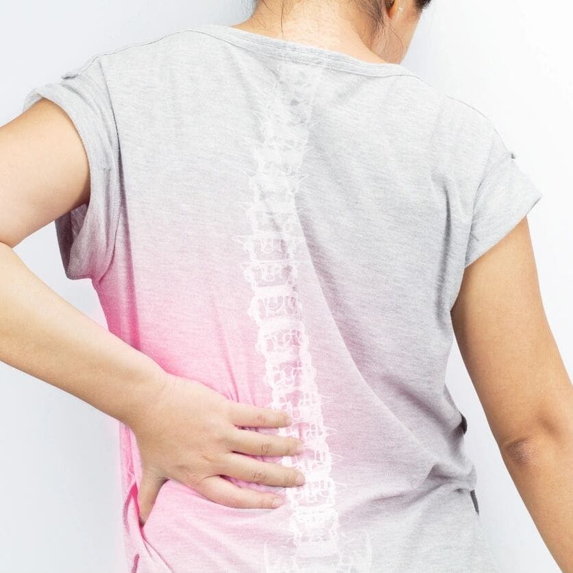 A man with his back turned holding on to the side of his body.