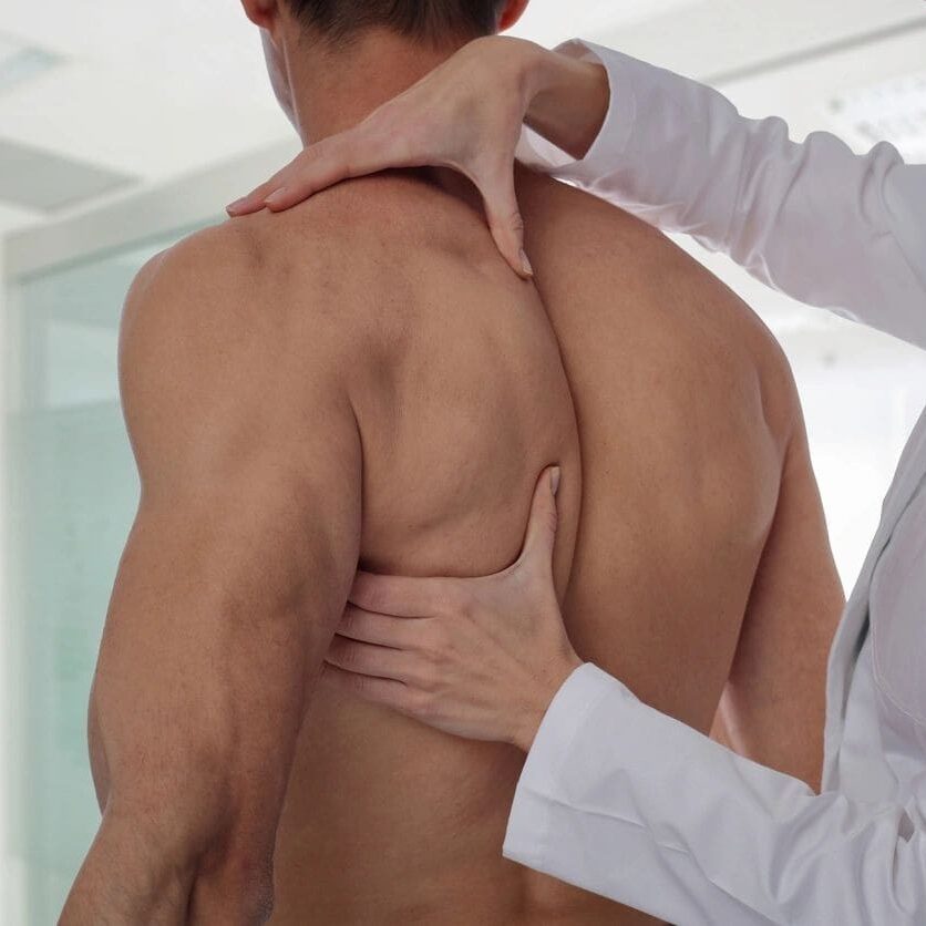 A person is holding their back while another person holds out his hand.