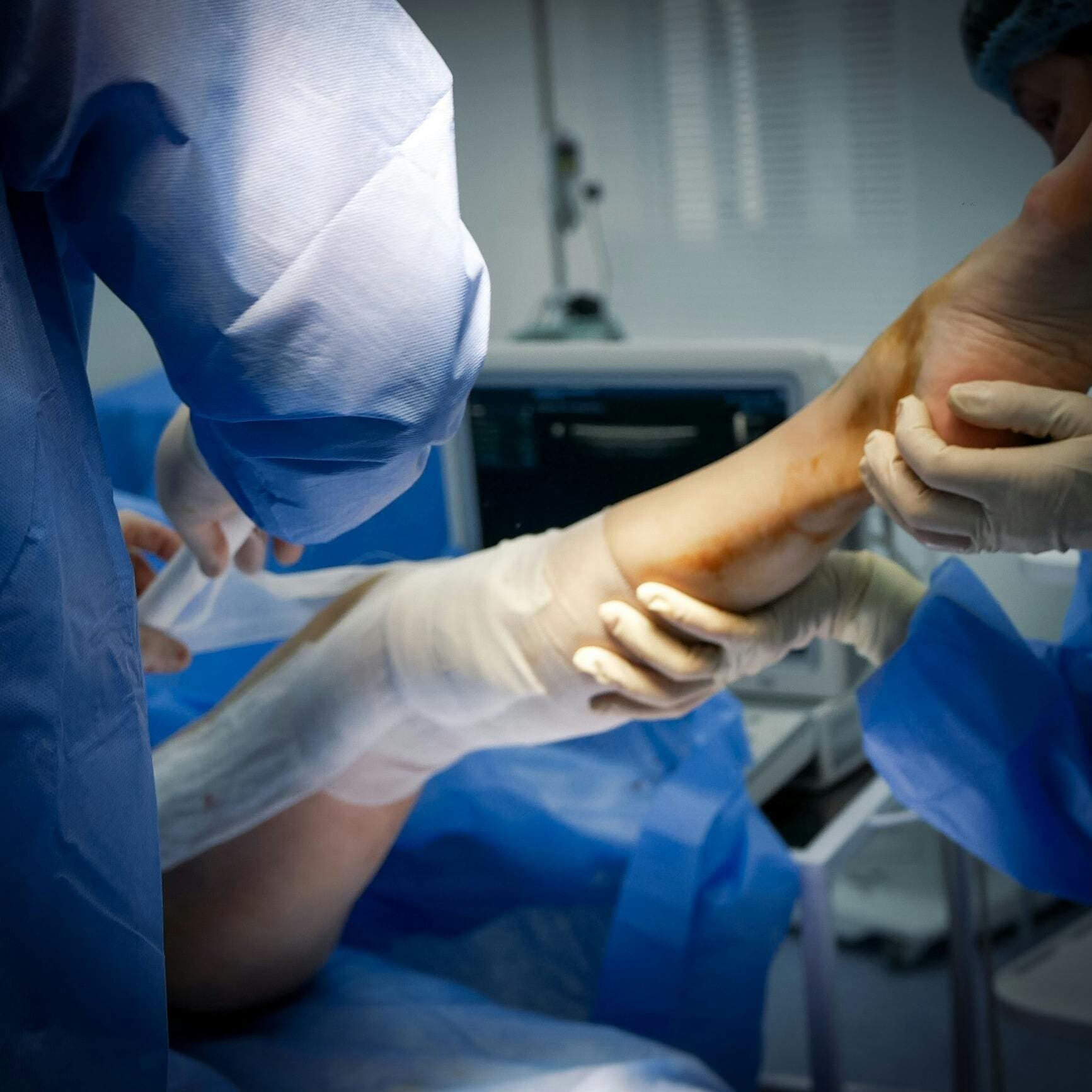 A surgeon is performing surgery on someone 's foot.