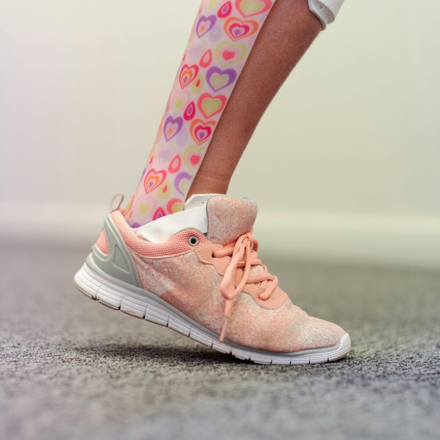 A person wearing pink and white shoes with hearts on them.