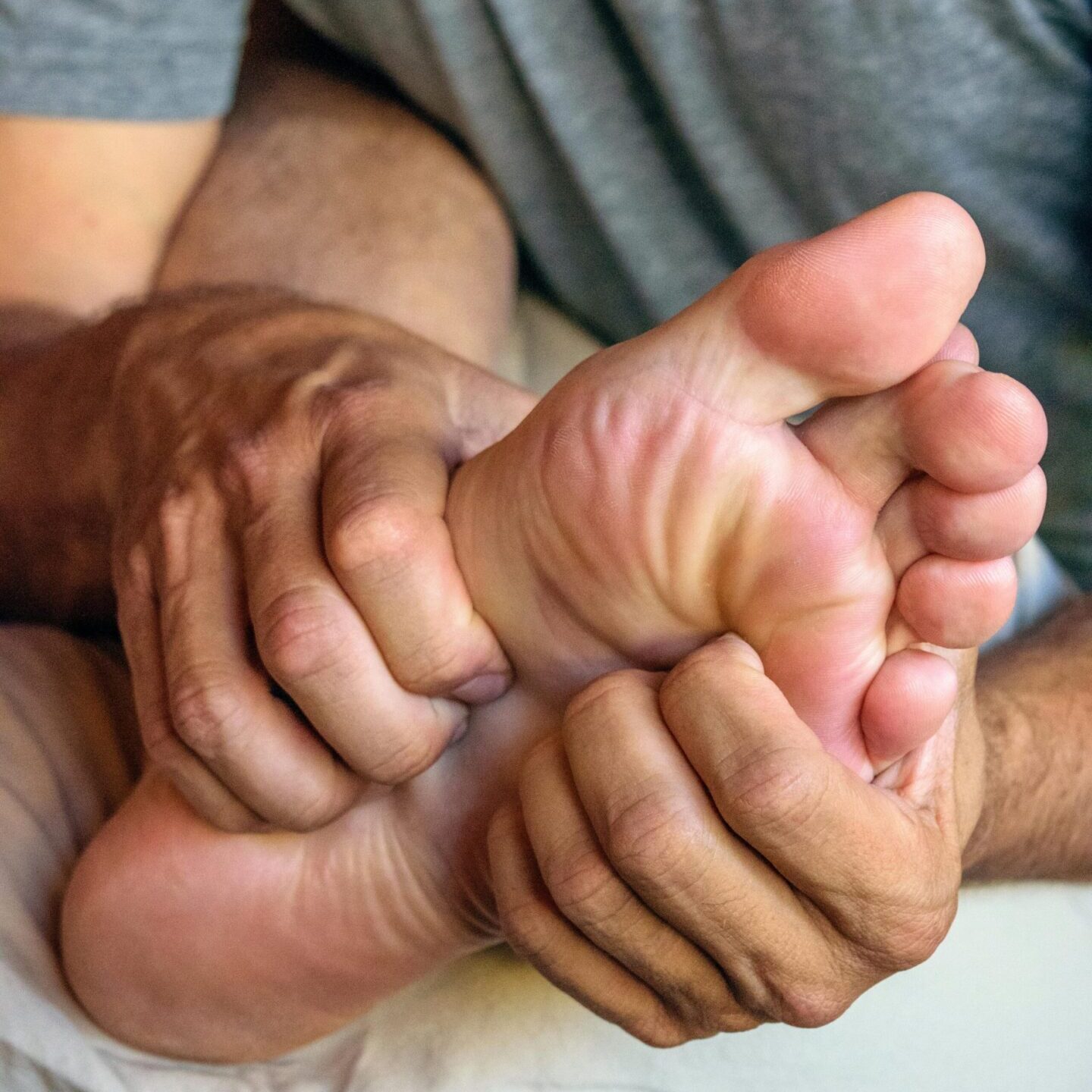A man holding his feet while another person holds them.