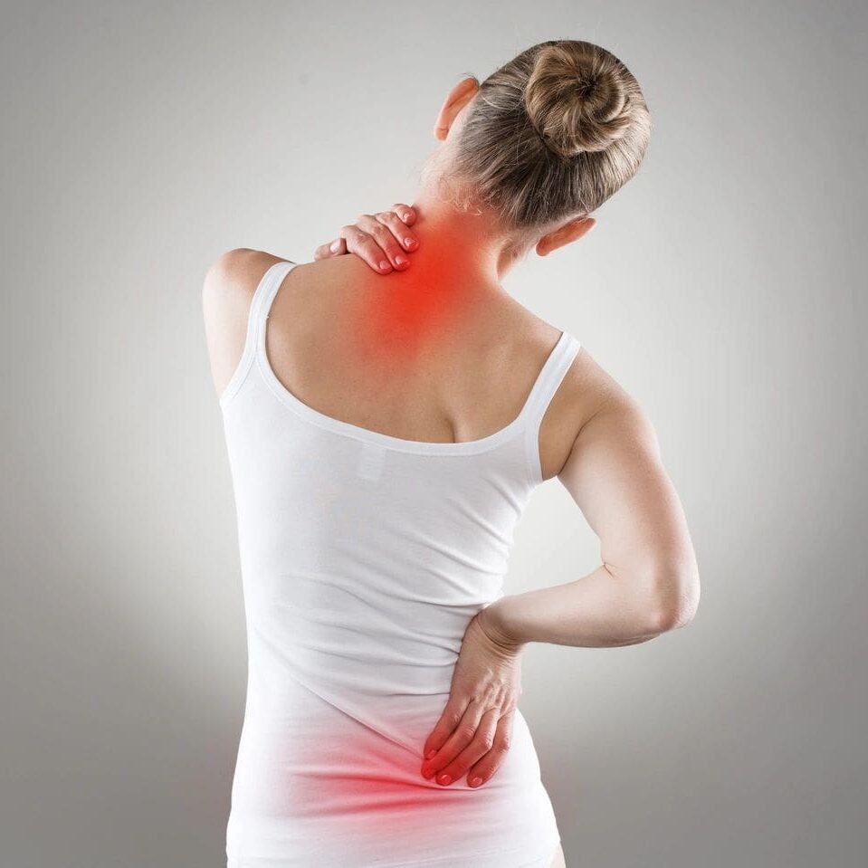 A woman in white shirt holding her back with red dot